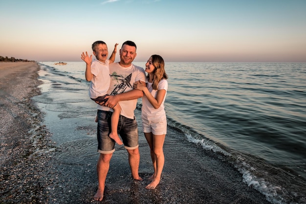 Retrato de família feliz na praia ao pôr do sol