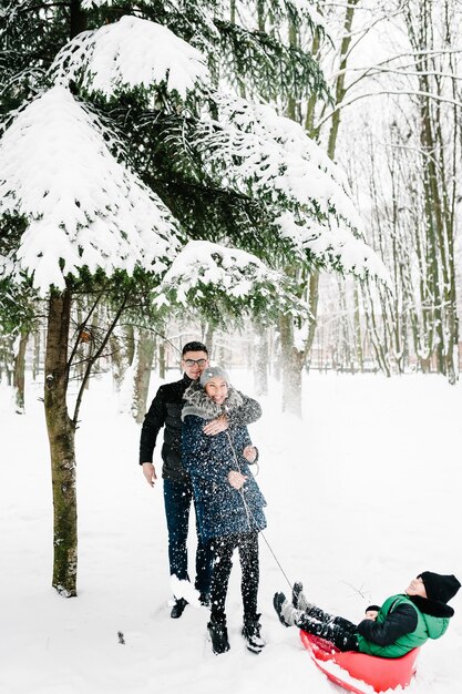 Retrato de família feliz soprando neve em winter park. Família brincando na caminhada de inverno nevado na natureza.