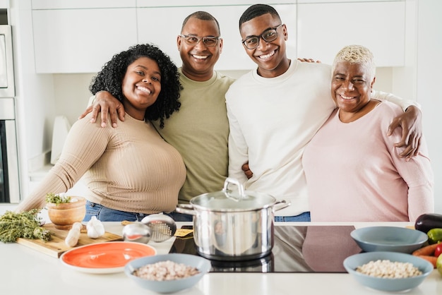 Retrato de família negra feliz cozinhando comida vegana dentro da cozinha em casa foco principal no rosto da mãe