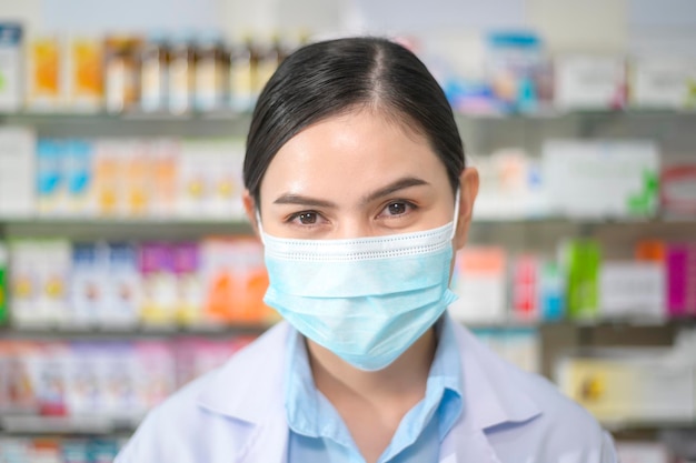 Retrato de farmacêutico feminino usando máscara facial em uma farmácia moderna