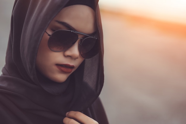 Retrato de Fashi da bela jovem muçulmana com o hijab preto e óculos de sol. Estilo vintage