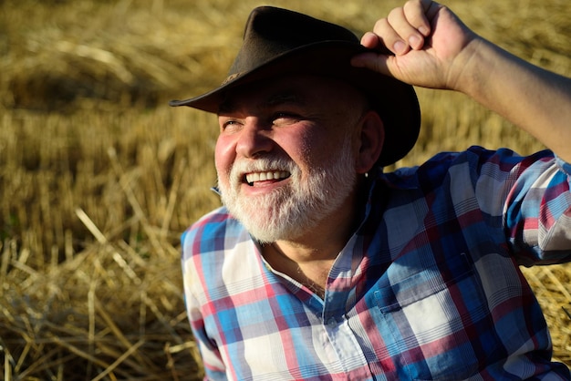 Foto retrato de fazendeiro maduro. agricultor sênior perto do campo após um árduo dia de trabalho.