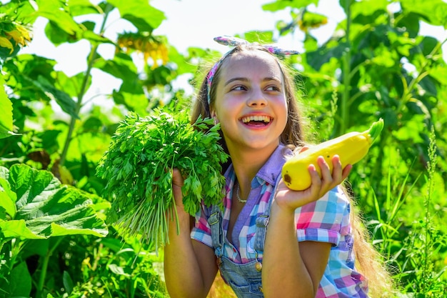 Retrato de felicidade de infância de criança feliz com criança retrô alegre de medula vegetal segura abóbora grande e salsa pequena menina cultivando na fazenda de verão feliz dia das crianças