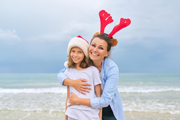 Retrato de feliz abraçando mãe e filha, pai e filho celebrando o Natal e ano novo juntos. Fundo do mar, oceano, praia, céu, conceito de viagens de férias em família