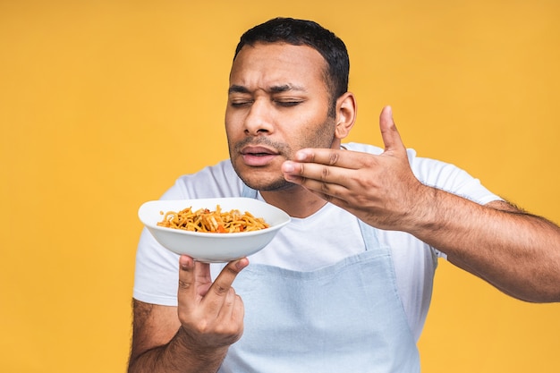 Retrato de feliz afro-americano indiano negro chef cozinhar macarrão. Conceito de culinária, profissão, alta cozinha, alimentos e pessoas isolado sobre fundo amarelo.