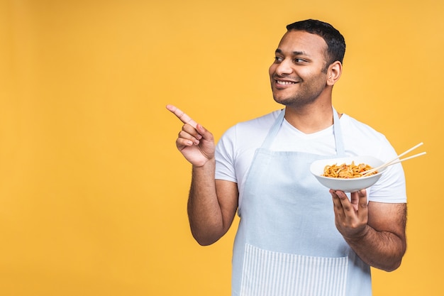 Retrato de feliz afro-americano indiano negro chef cozinhar macarrão. Conceito de culinária, profissão, alta cozinha, alimentos e pessoas isolado sobre fundo amarelo.