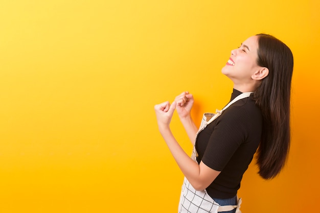 Retrato de feliz cozinheiro feminino em fundo amarelo