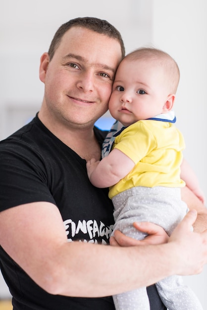 Foto retrato de feliz jovem pai segurando bebê recém-nascido perto da janela em casa