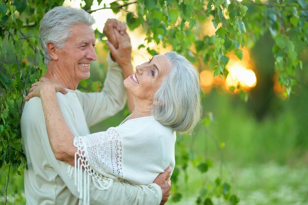 Retrato de feliz lindo casal sênior dançando no parque de verão