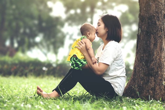 Retrato, de, feliz, mãe bebê, menina, beijando, e, abraçando, parque