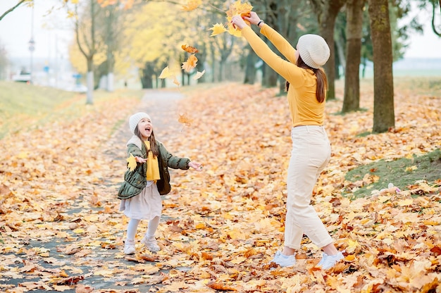 Retrato de feliz mãe e filha na floresta de outono ao pôr do sol. jovem mãe e filha caminhando no parque outono. mulheres de outono.