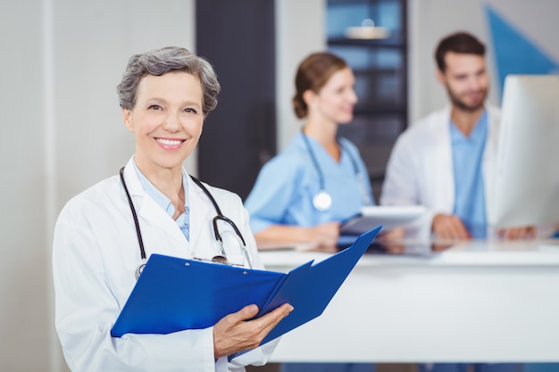 Retrato de feliz médico feminino segurando relatórios médicos