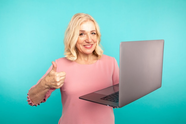 Foto retrato de feliz saiu da senhora abulta com laptop isolado sobre o estúdio azul.