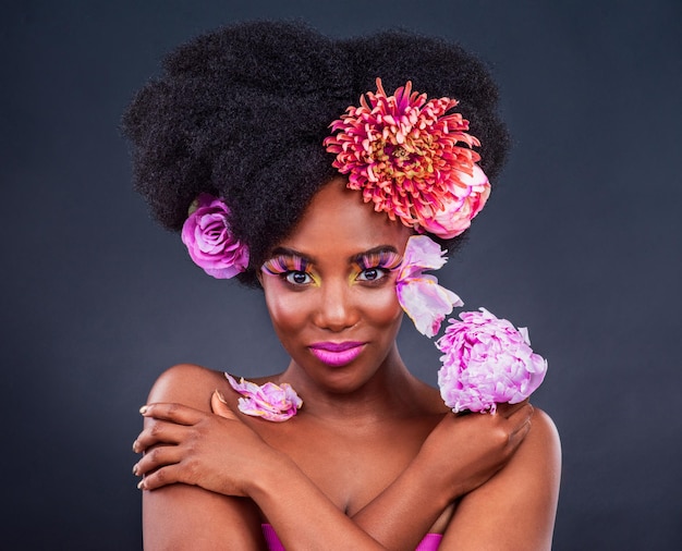Retrato de flores e mulher negra com maquiagem em estúdio para beleza orgânica em fundo escuro Rosto floral e modelo de senhora africana sorriem para produtos naturais e cosméticos ecológicos com maquete isolada