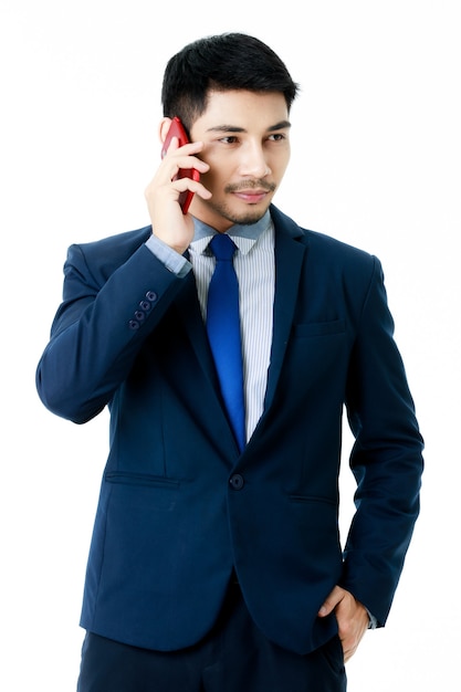 Retrato de focado jovem empresário asiático fala ao telefone em fundo branco isolado. tiro do estúdio, conceito de comunicação empresarial.