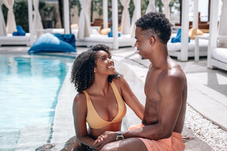 Retrato de foco suave de um casal afro-americano amoroso sentado perto da piscina e se beijando. Phuket. Tailândia. Viagem ao destino quente