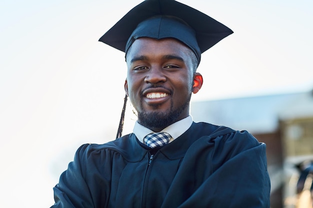 Retrato de formatura e chapéu para homem preto orgulhoso e ao ar livre com sorriso e felicidade para o objetivo realização pessoa e estudante em evento universitário e celebração para a educação e se formar com alegria