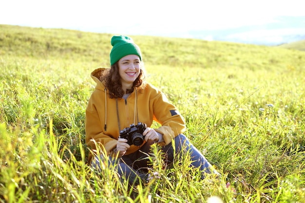 Retrato de fotógrafo de mulher encaracolada ao ar livre. Mulher anda e tira fotos com sua câmera