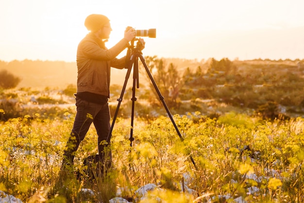 Retrato, de, fotógrafo, fazer, fotos, com, câmera tripé, em, pôr do sol