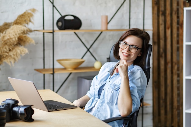 Foto retrato de freelancer feminino sorridente usando laptop.