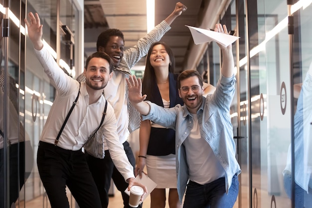 Foto retrato de funcionários diversos felizes comemorando a vitória nos negócios equipe animada se divertindo na festa corporativa sorrindo e rindo colegas olhando para a câmera em pé no corredor do escritório moderno