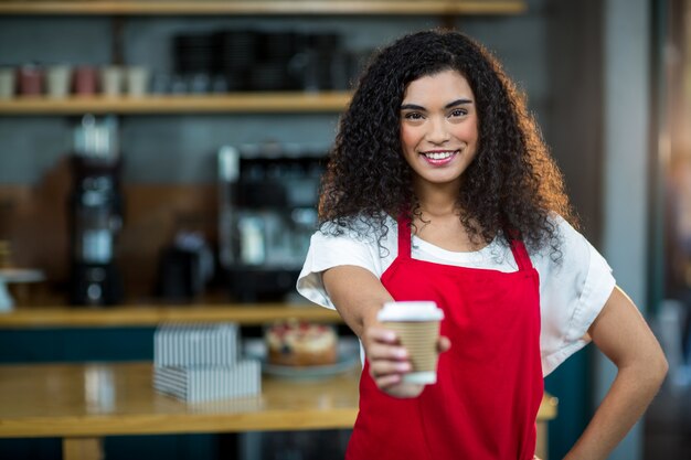 Retrato de garçonete mostrando a xícara de café descartável