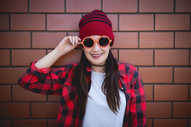 Retrato de garota hipster asiática no fundo da parede de tijolosEstilo de vida do povo da tailândia