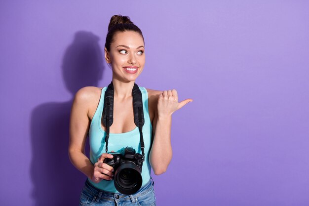 Retrato de garota viajante positiva segurando câmera digital apontar polegar dedo copyspace