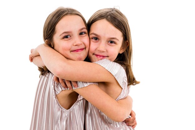 Foto retrato de gêmeos sorridentes abraçados contra um fundo branco