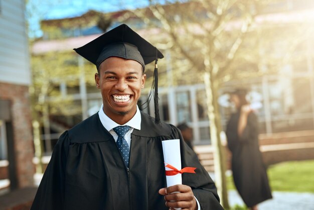 Retrato de graduado e homem negro com pergaminho em certificado ou diploma universitário na Nigéria Estudante masculino felicidade e orgulho de realização com celebração de sucesso ou prêmio no campus para o evento