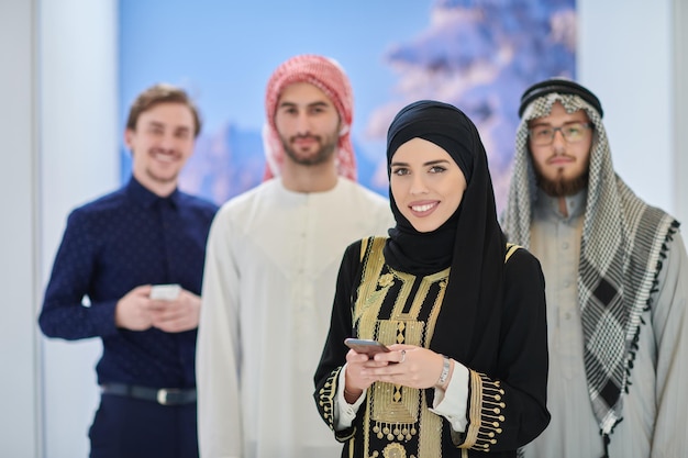 Retrato de grupo de empresários muçulmanos e empresária. Árabes em roupas tradicionais usando smartphones e representando moda e tecnologia islâmicas
