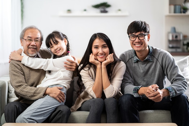 Retrato de grupo de família asiática feliz sentado no sofá-sofá na sala de estar com um sorriso