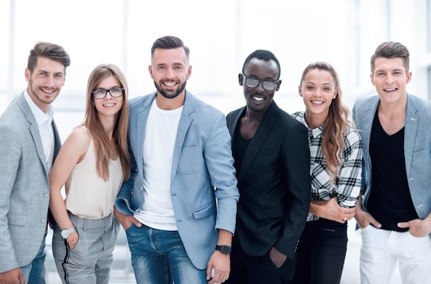 Retrato de grupo de pessoas felizes casuais em pé com as mãos nos bolsos sobre fundo branco