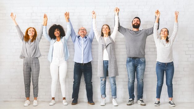 Foto retrato de grupo de teambuilding de pessoas felizes segurando e levantando as mãos juntas