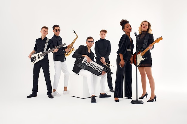 Foto retrato de grupo diversificado de banda musical de jovens tocando com instrumentos isolados no fundo branco