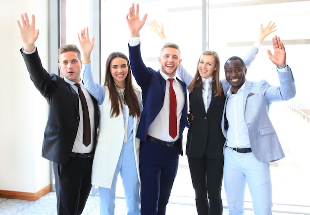 Retrato de grupo empresarial de sucesso acenando com as mãos no escritório