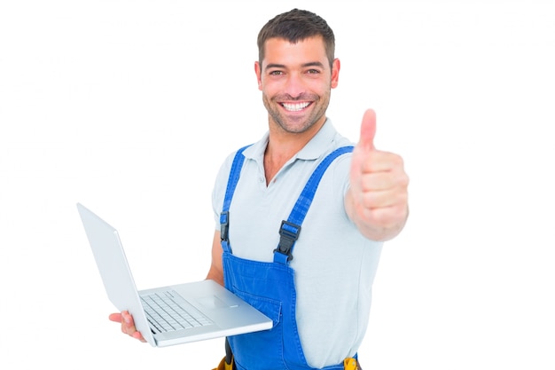 Retrato de handyman com laptop gesticulando polegares para cima