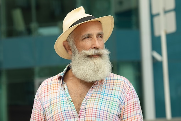 Retrato de homem adulto bonito elegante com barba em pé ao ar livre.