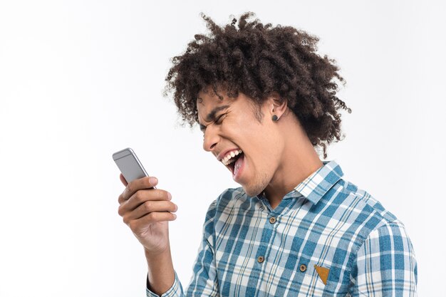 Retrato de homem afro-americano gritando em smartphone, isolado em uma parede branca