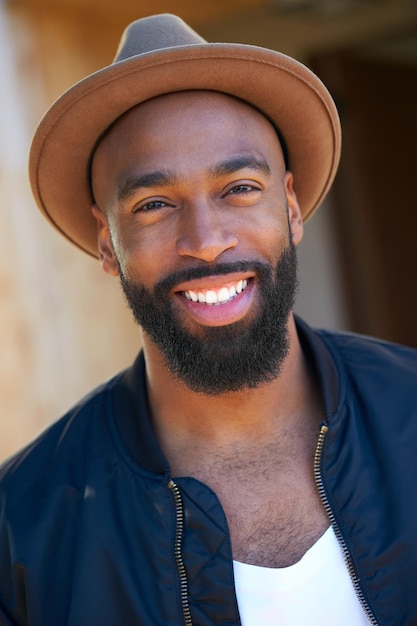 Retrato de homem afro-americano sorridente usando chapéu no jardim em casa