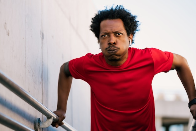 Retrato de homem afro atlético fazendo exercício ao ar livre. esporte e estilo de vida saudável.