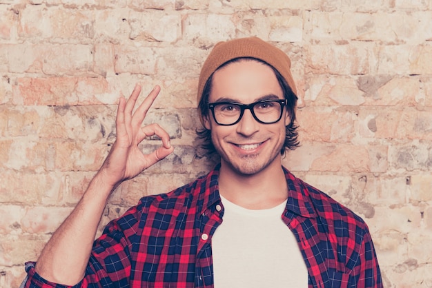 Retrato de homem alegre hippie de óculos gesticulando ok