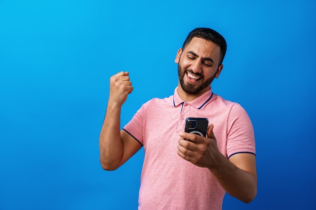 Retrato de homem árabe usando seu smartphone em estúdio