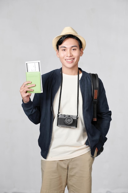 Retrato de homem asiático animado surpreso segurando passaporte e passagem de cartão de embarque