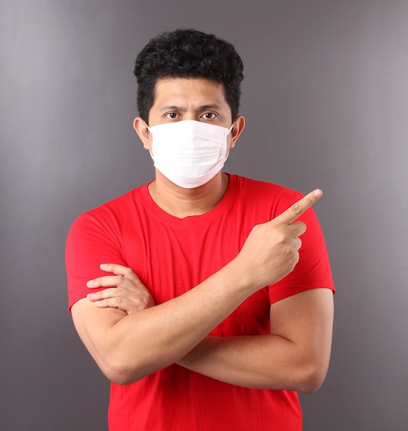 Retrato de homem asiático bonito vestindo uma máscara está doente apontando o dedo