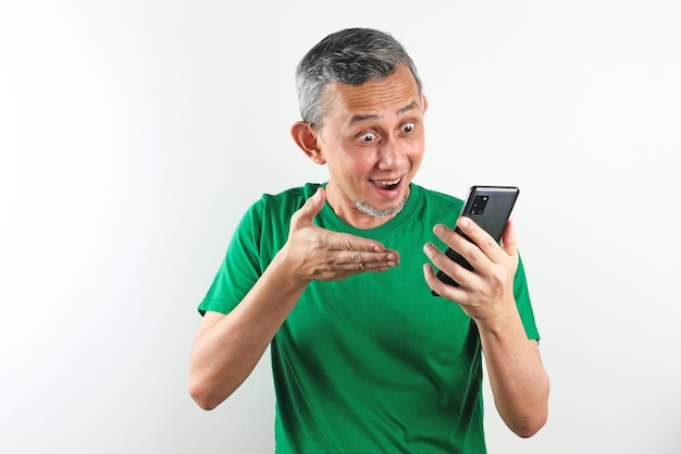 Retrato de homem asiático com camisa casual posa feliz com a mão segurando o celular