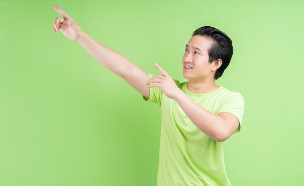 Retrato de homem asiático em camiseta verde, posando em verde.