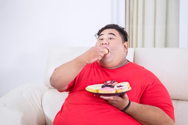 Retrato de homem asiático gordo olhando para um donut