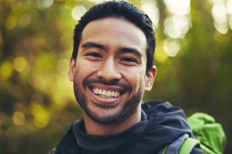 Foto retrato de homem asiático ou caminhadas na natureza floresta trekking bosques ou ambiente de árvores para treino de aventura ou exercício físico sorriso feliz ou rosto de caminhante de treinamento em liberdade de viagem ou aventura divertida