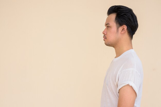 Retrato de homem asiático vestindo camiseta branca casual contra um fundo liso ao ar livre